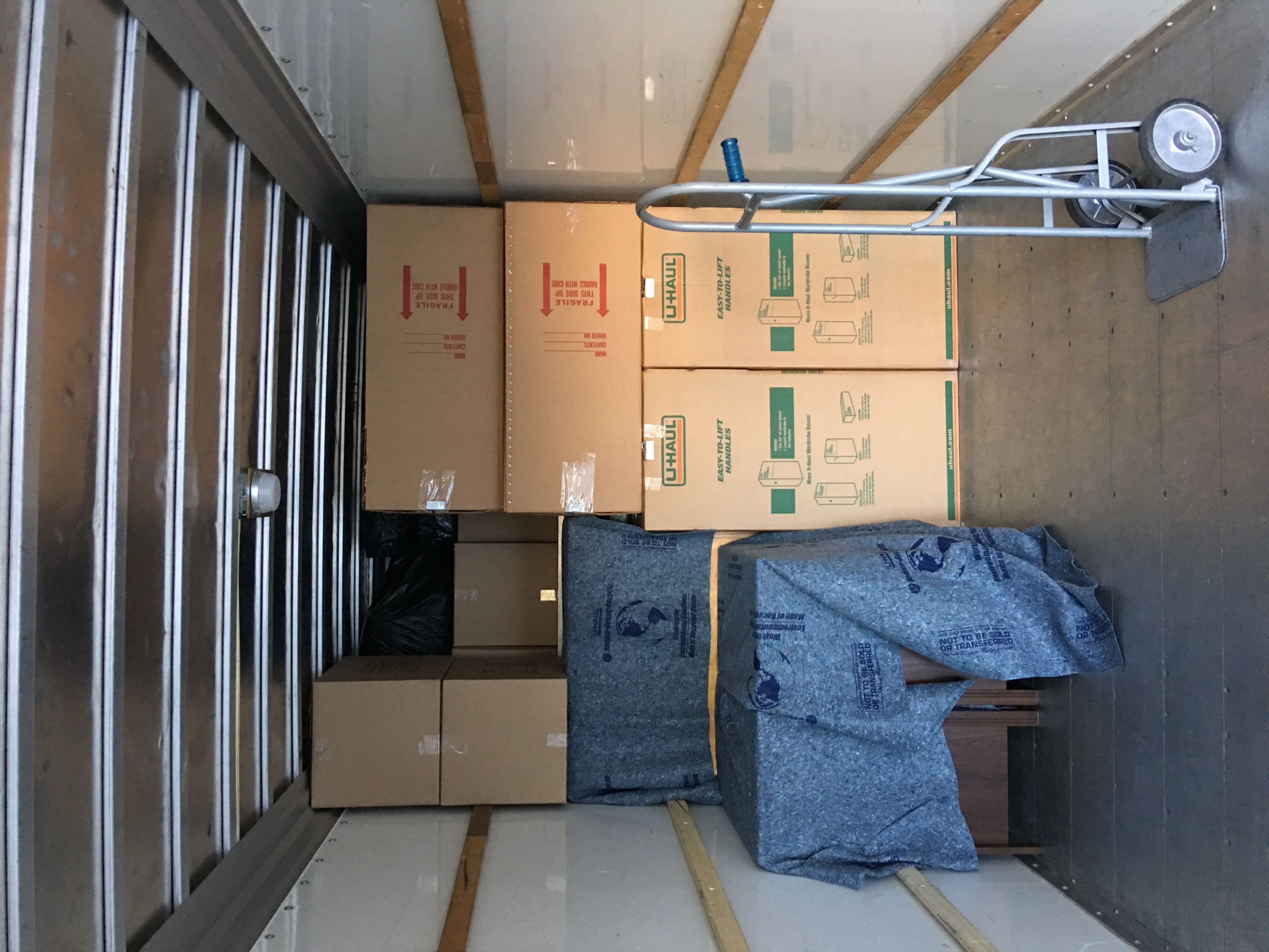 A neatly stacked truck with U-Haul boxes and a dolly